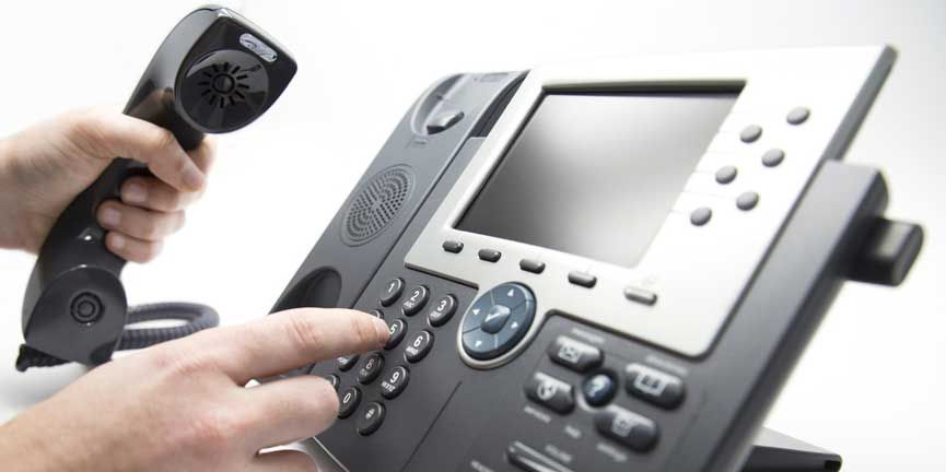 employee hand dialing keypad on IP phone