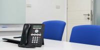 Though not readily apparent, there are a number of conference call factors that cause companies to lose both time and money. conference calling phone on desk in meeting room