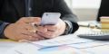 businessman at desk on smartphone sending sms message