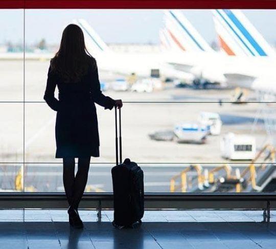 Travel industries can use a VoIP system to help clients discover the best travel opportunities available. woman at airport traveling with suitcase